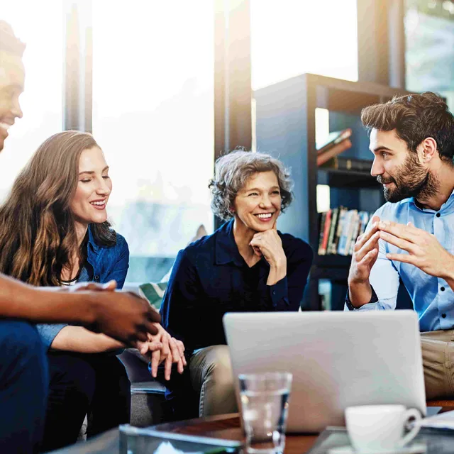 Group of professionals engaged in a collaborative discussion around a laptop.