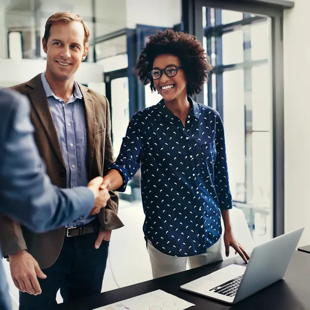 Business professionals shaking hands in an office, highlighting Berlitz’s corporate language training programs for professional communication success.