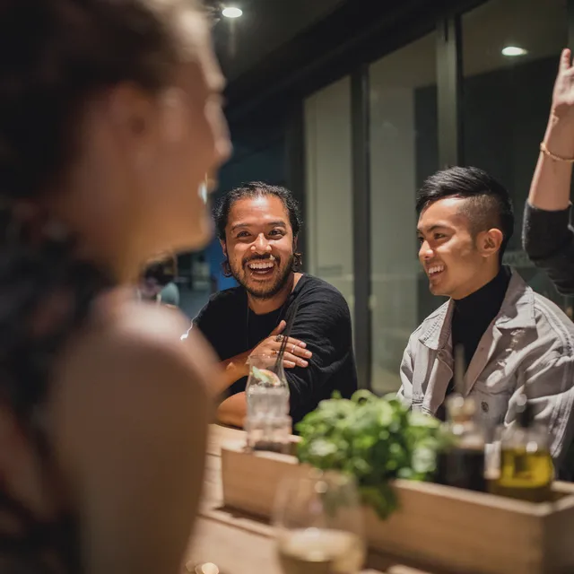 Group of young adults enjoying a lively conversation at a restaurant, reflecting Berlitz’s focus on social confidence through language immersion.
