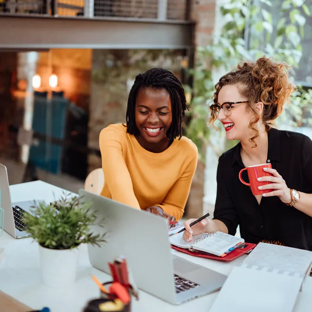 Two women collaborating in a modern office, capturing the dynamic and supportive work culture promoted through Berlitz careers.
