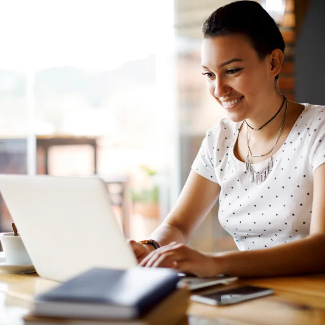 Smiling young professional working remotely on a laptop, representing the flexible and global opportunities available through Berlitz careers.